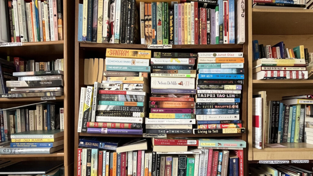 Three shelves of books stacked tightly together in a room.