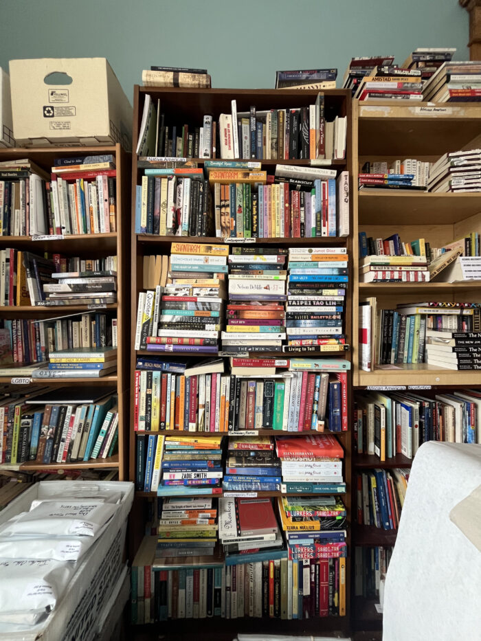 Three shelves of books stacked tightly together in a room.