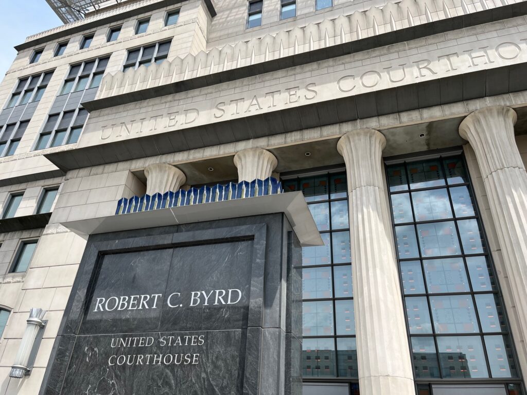 An overbuilt marble building with garish details looms over a marble slab that looks like a tombstone but merely displays the name of a dead man who was in the Senate for long past his prime.