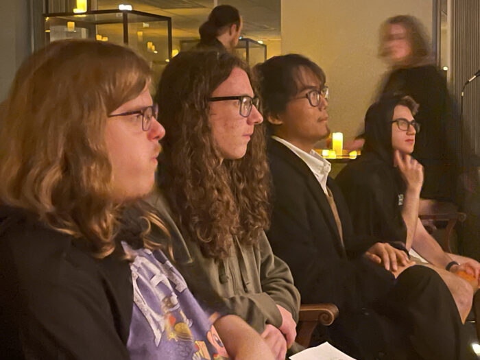 Four Marshall students are shown listening to a speaker from a profile angle.