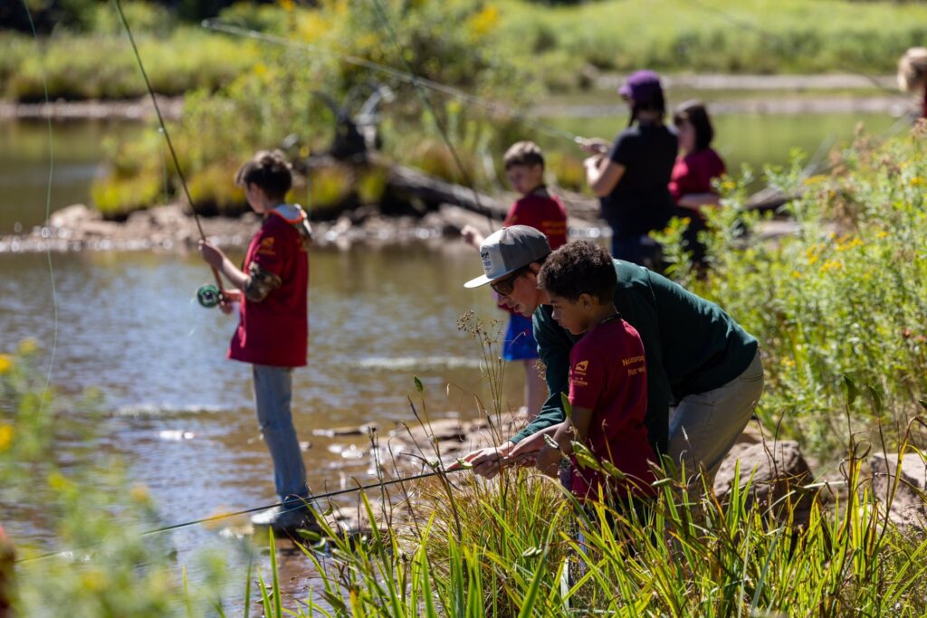 young people standing in a stream fishing