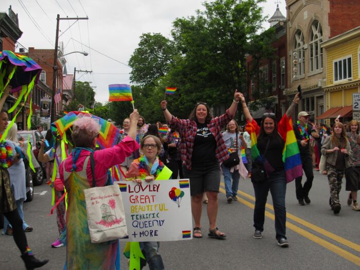 People wearing rainbow attire process through the street in a parade.