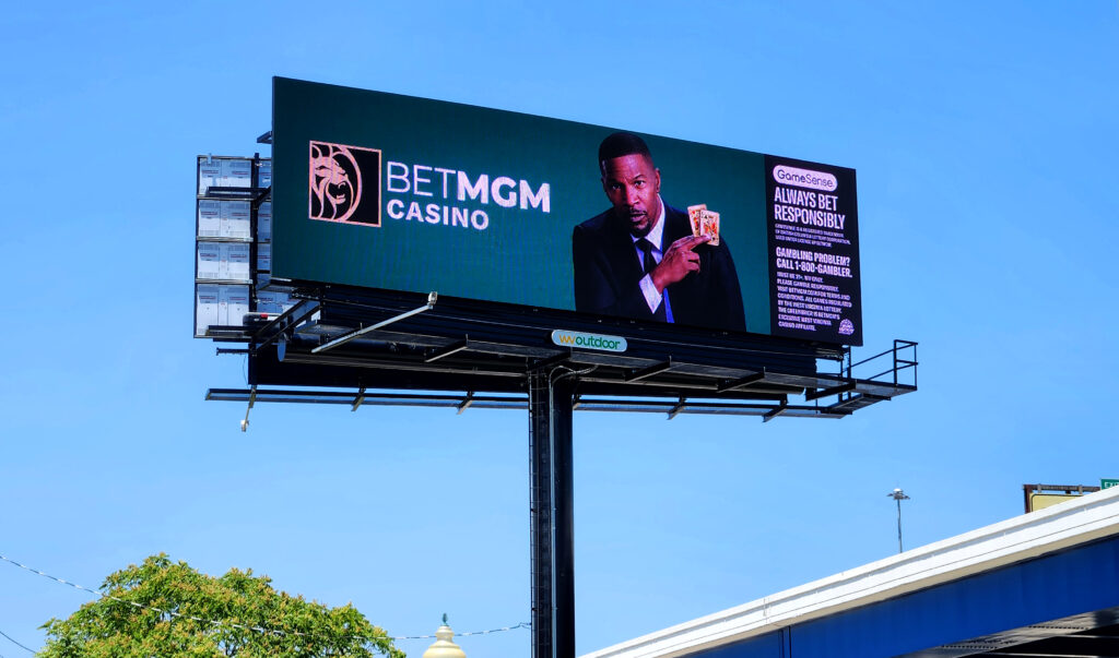 billboard in the sky with a man in a suit holding up playing cards