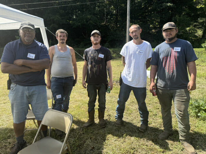 Five people standing outside facing a camera.