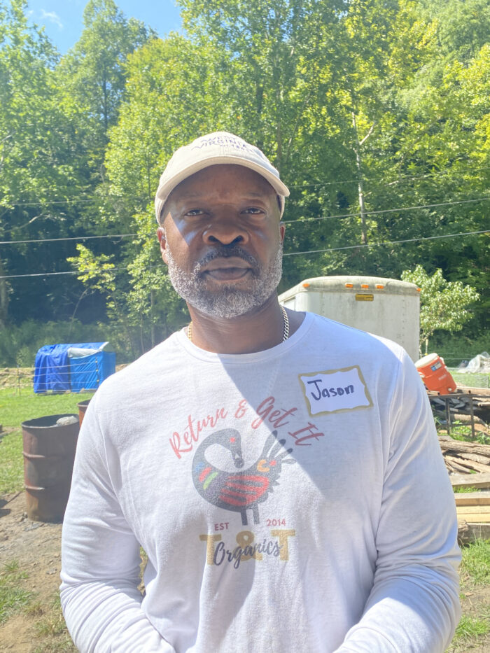 Portrait of a Black man standing outside on a sunny day wearing a white t-shirt. 