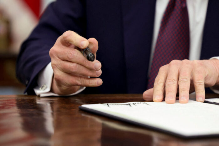 Close up of hands holding a pen, ready to sign a document.