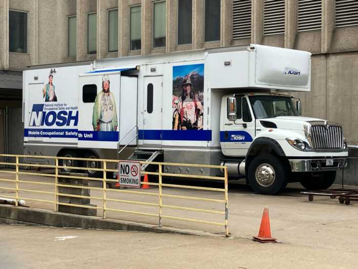 A large truck that looks like a bookmobile sits outside an office building on an overcast day.
