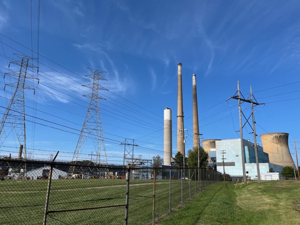Transmission lines and power plant infrastructure are set against a clear sky on a late summer day.