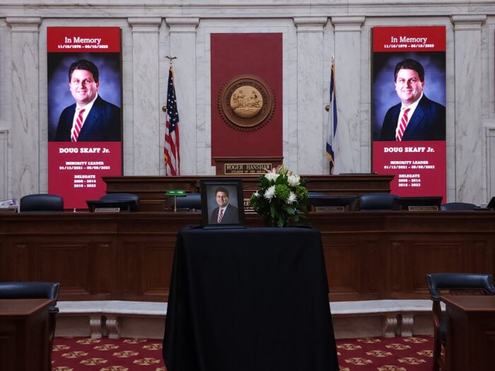 Photos and banners of a man in a dark suit on a table draped in black