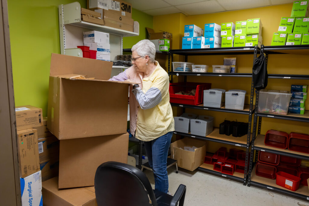Woman with short gray hair digs into a box in a store room