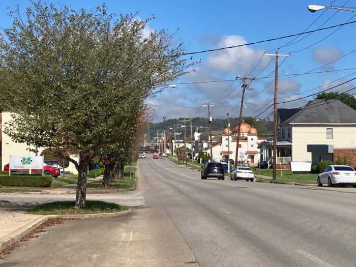 A view of a street. There is a tree and a couple of buildings visible on either side of the street.