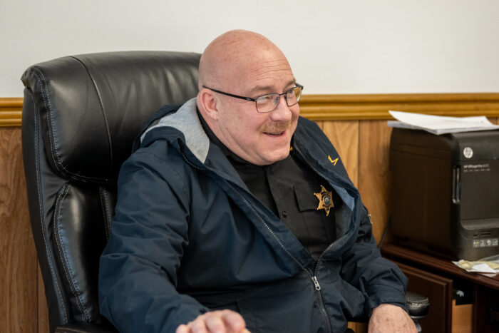 Bald law enforcement officer sitting at a desk chair. 