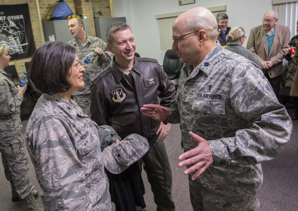 Three people. Two men and one woman. They are dressed in military outfits and look away from the camera.