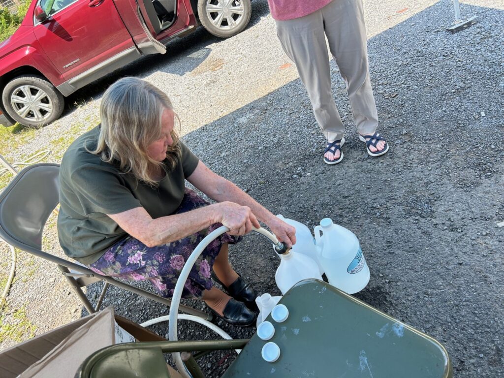 Woman holding a plastic jug and a hose