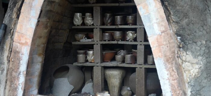 A photograph of a wood-fire kiln filled with shelves of pottery. 