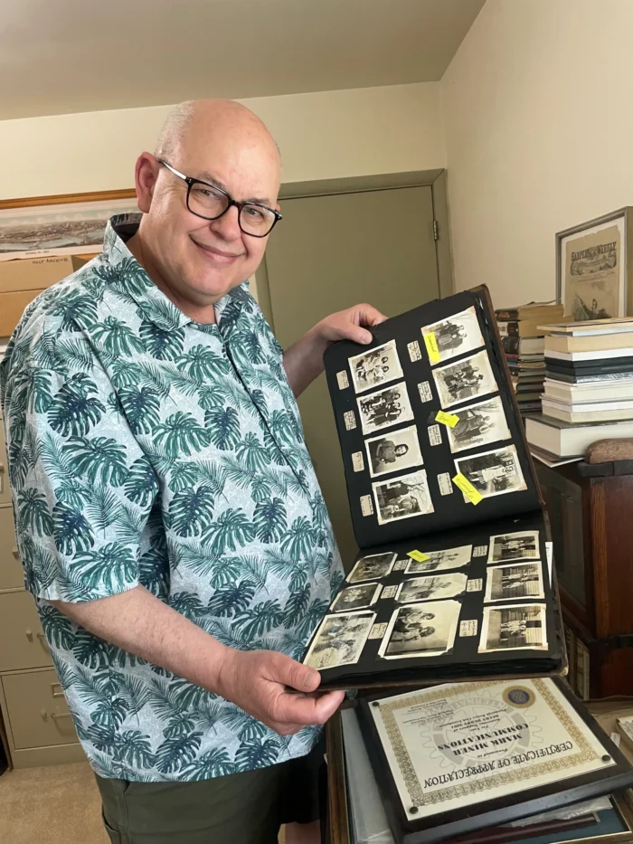 A white man holding a book of photos. 