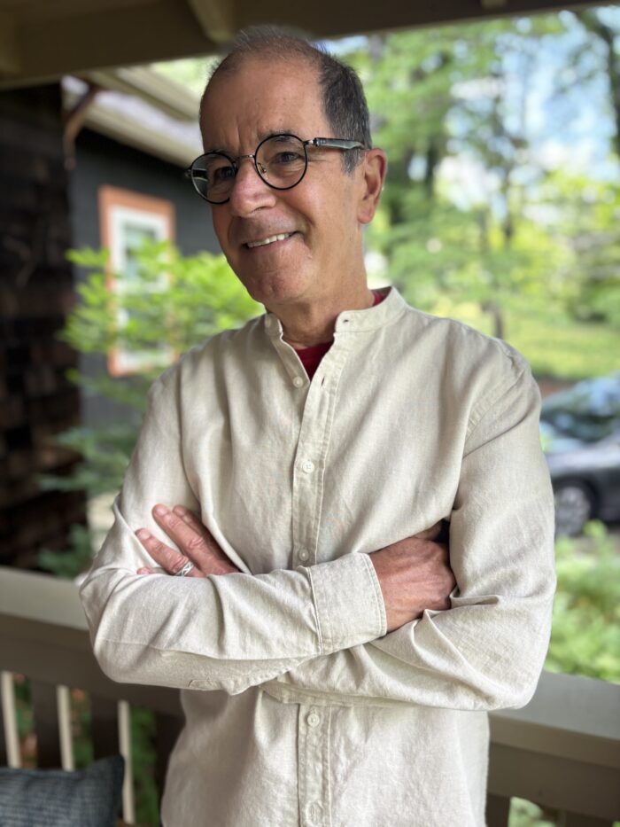 A white man wearing a white shirt standing outside. 