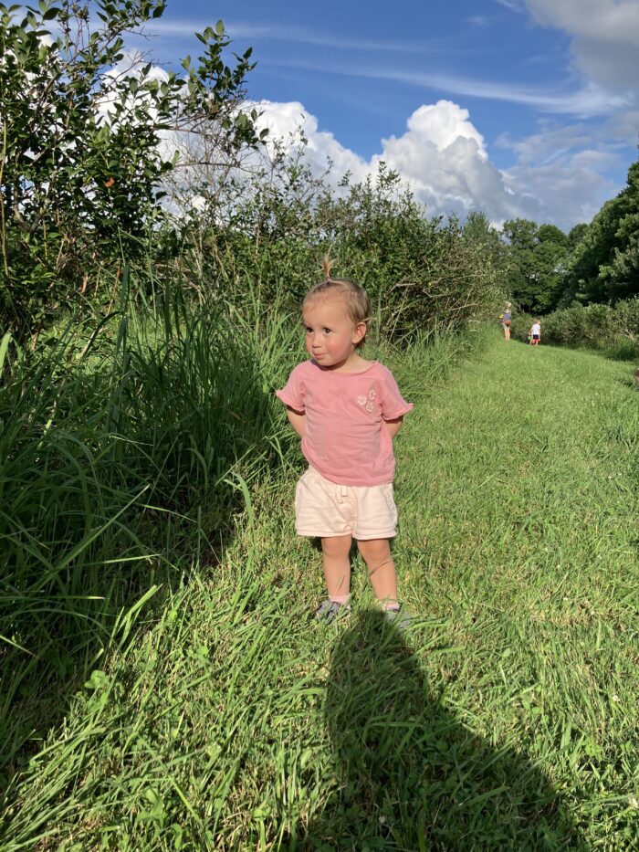 A little girl, about 2.5 years old, stands outside