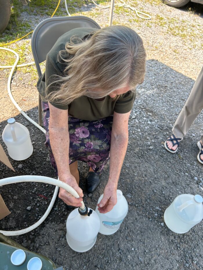 Woman fills water jugs from hose