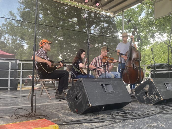 Four people playing musical instruments on a stage.