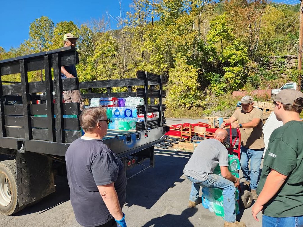 people unload water bottles from the back of a truck