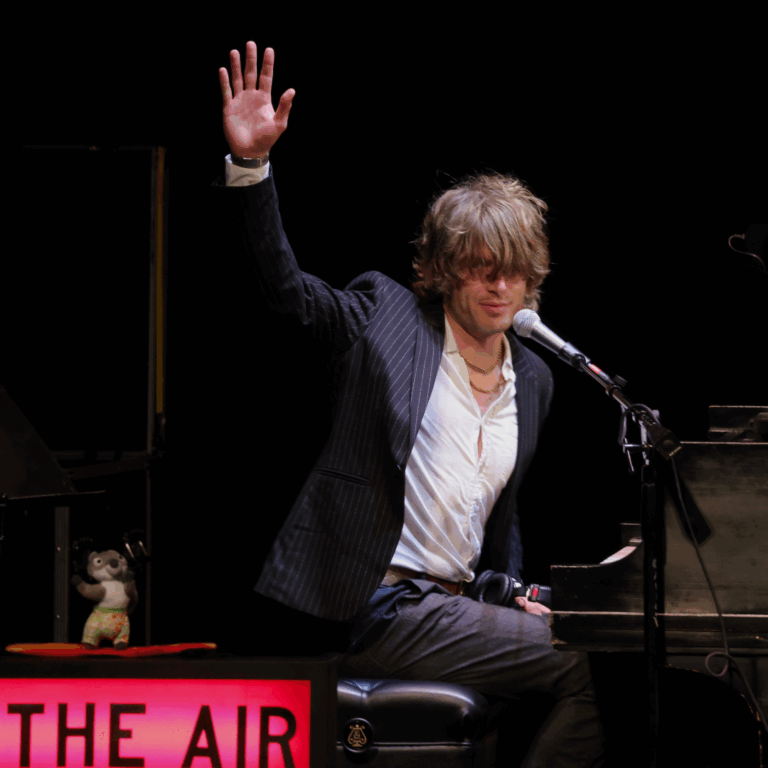 man on piano waves to crowd