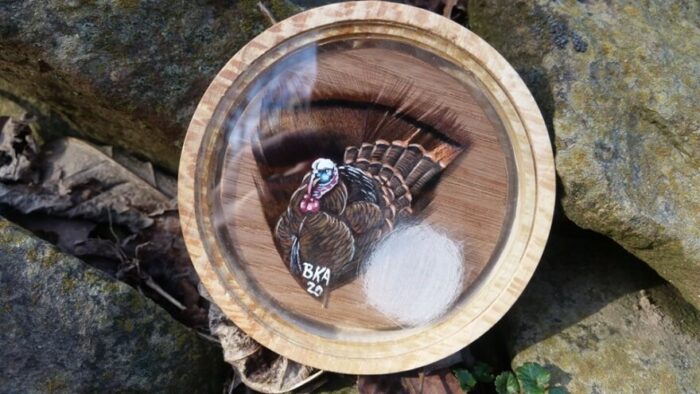 A wooden turkey call on top of rocks. 