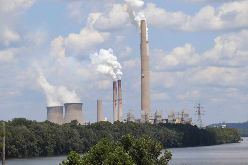 Several smokestacks are seen in the distance against a cloudy, blue sky.