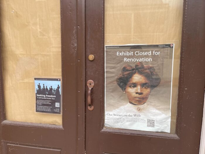 A close up photo of a window covered in brown paper. A Black woman from the Civil War is seen on a poster. The poster reads, "Exhibit closed for renovations."
