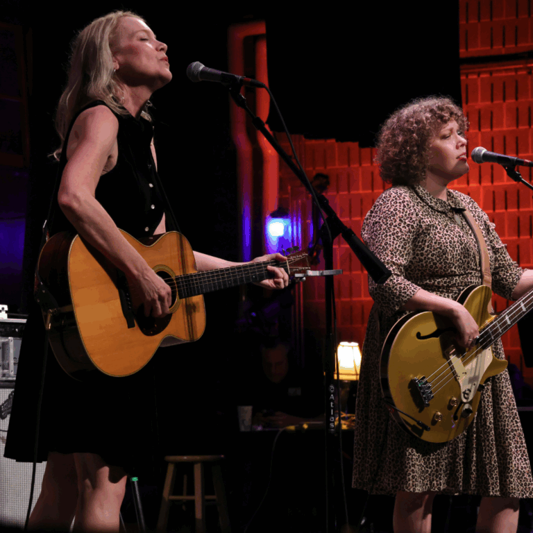 two women singing and holding guitar