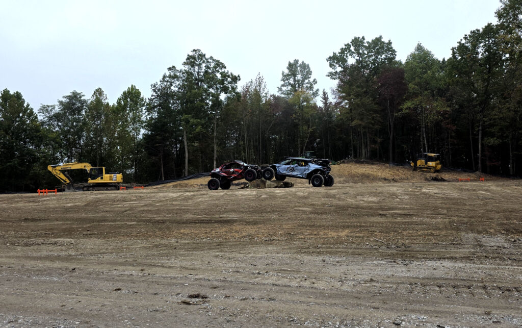 2 four wheel drive vehicles are positioned in a dirt field