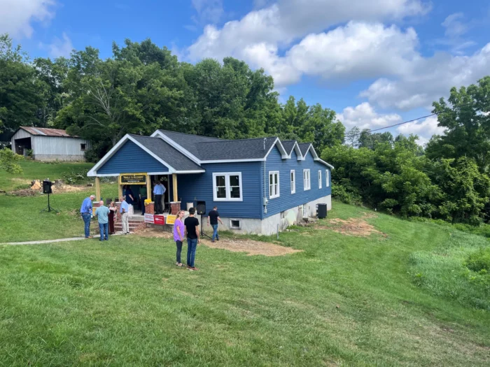 People standing around a blue house.
