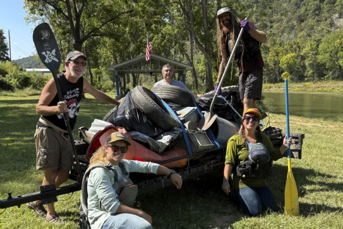 Five people standing around a pile of garbage pulled from a river.