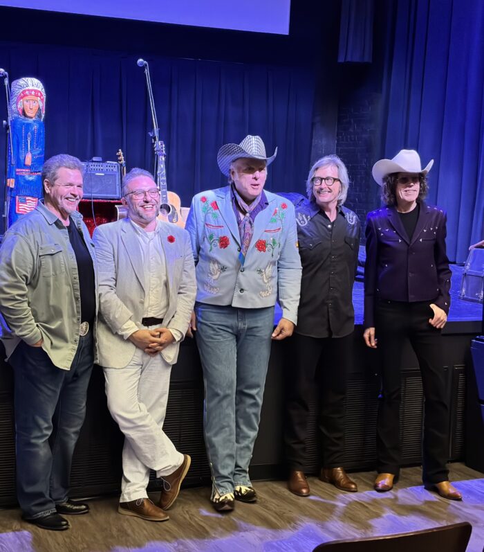 Five people standing in front of a dimly lit stage.
