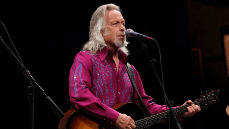 grey hair man plays guitar and sings