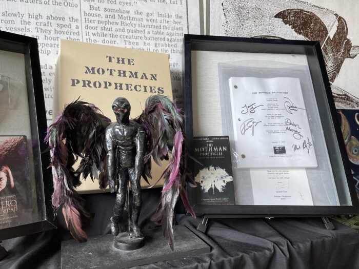 Inside the Mothman Museum in Point Pleasant, WV. A small statue is seen on a shelf text to a framed script from the Mothman Prophecies film. The script has been signed by the actors of the film.