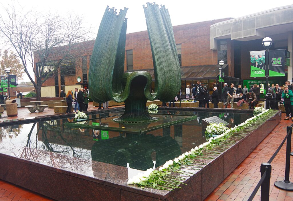 people milling around behind a large fountain.