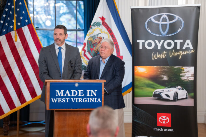 Two men stand behind a podium in suits