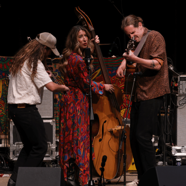 three musicians sing and play instruments