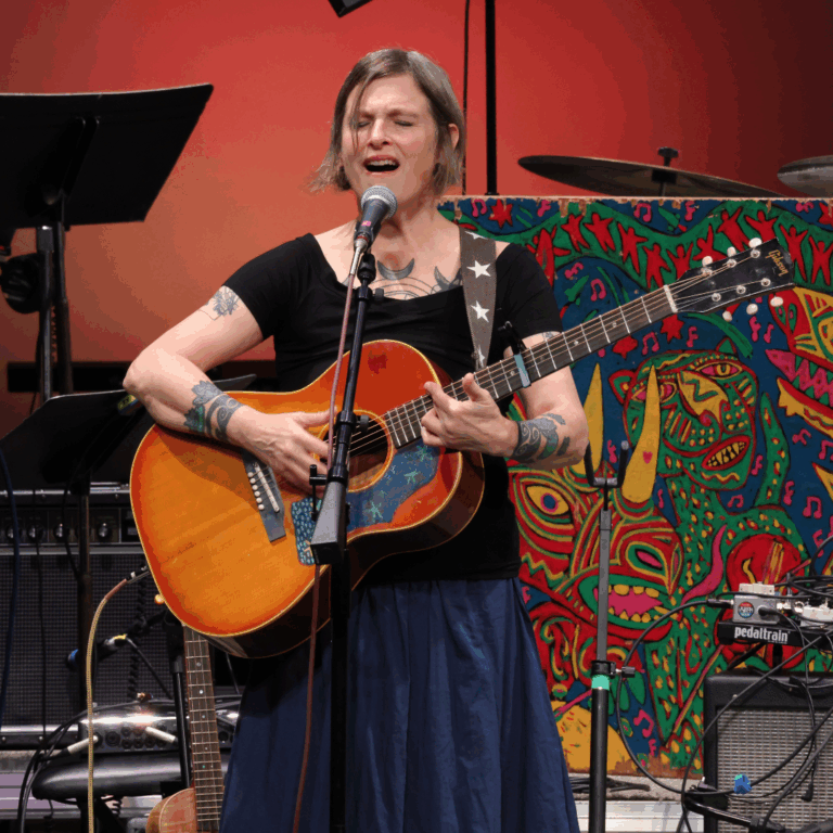 woman plays guitar and sings