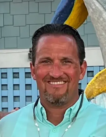 A man in his 40s faces the camera, smiling.