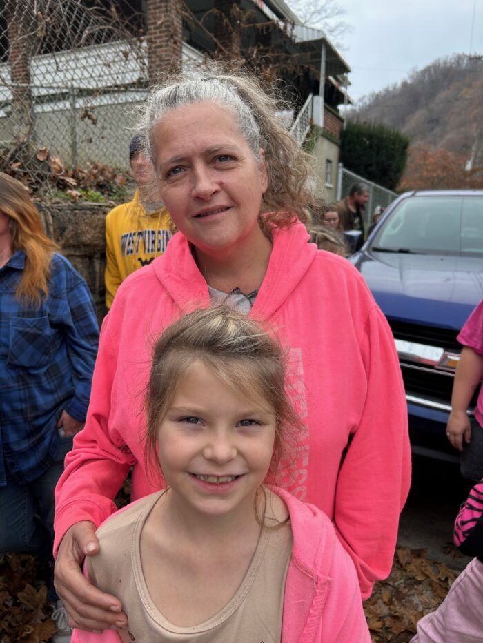 Two people, a woman and child, a grandma and her granddaughter stand together, posing for a photo.