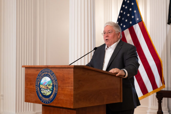 Man with gray hair stands behind a wooden podium