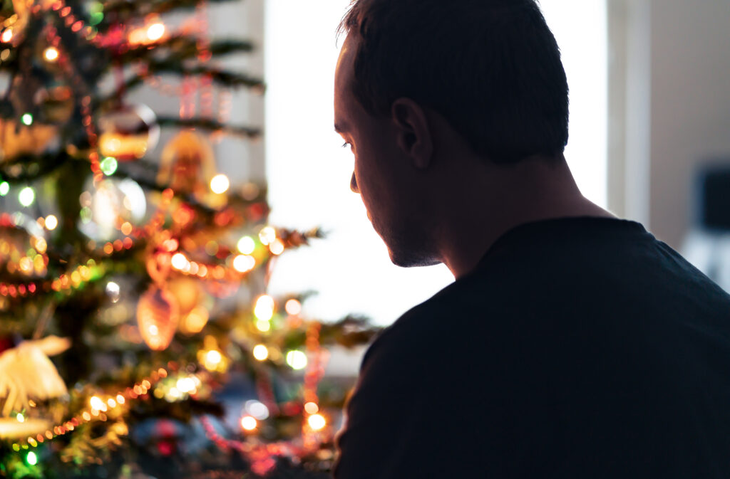 Silhouette of man looking at Christmas tree