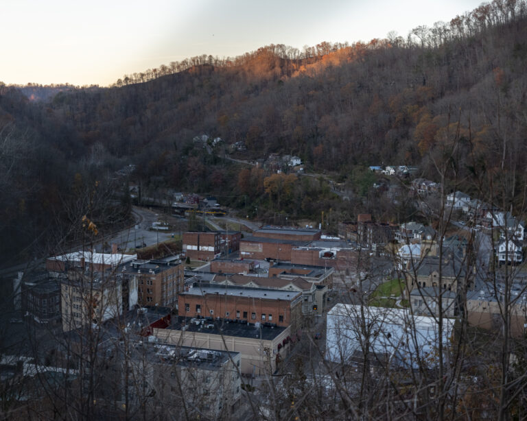 A faraway photograph of a rural town against the backdrop of a hill.