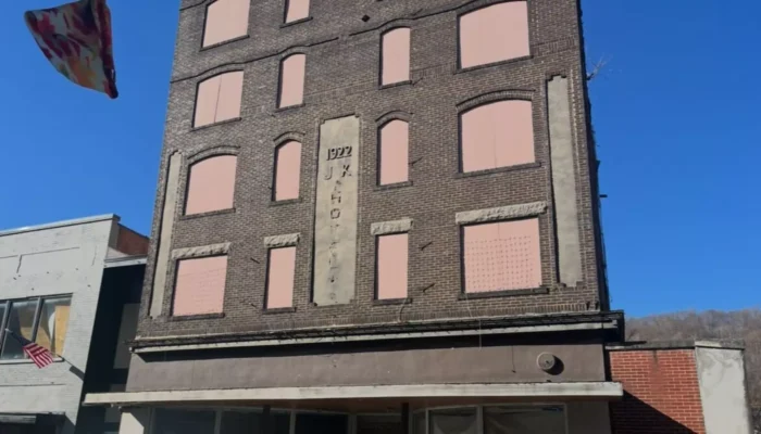 A street view of a building. The windows are boarded up. 
