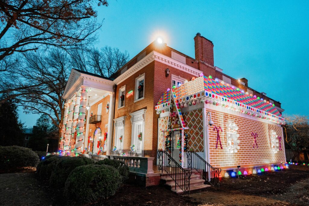 An ornate brick home is decked out in white lights and colorful decorations.
