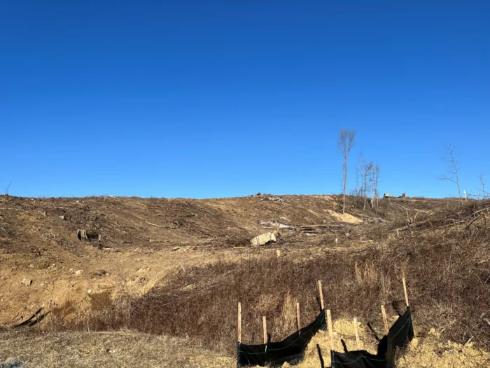 A landscape photo of a dirt field with a blue sky behind it.