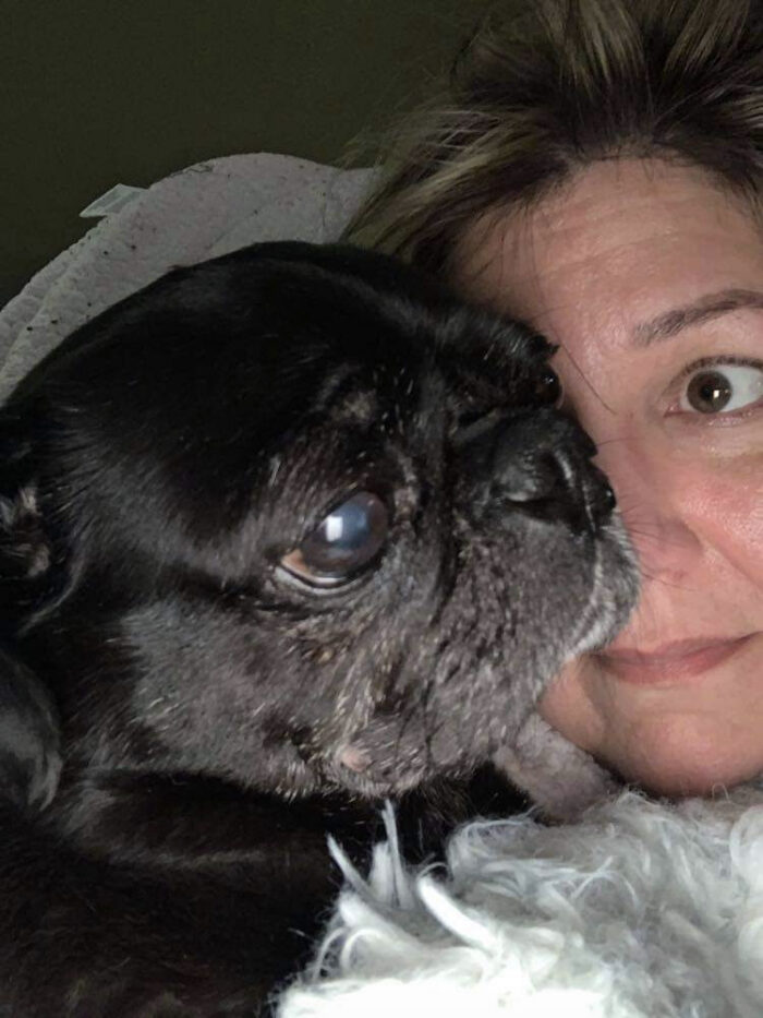 A selfie of a middle aged woman with her small black dog.