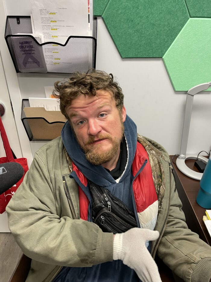 Young man in a coat and a light beard looks at camera